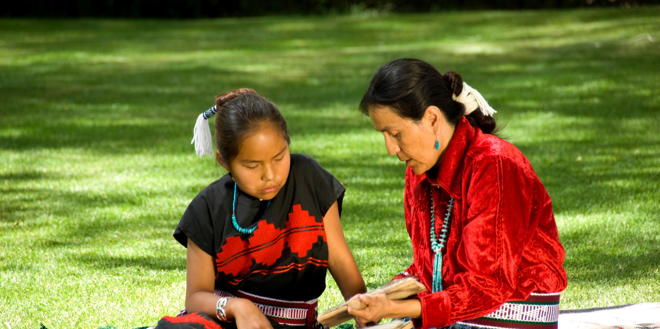 Indigenous elder teaches child to weave