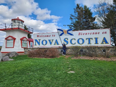 Team member standing in front of Welcome to Nova Scotia sign
